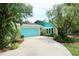 Landscaped single-story home featuring a turquoise garage door, lush greenery, and a well-maintained driveway at 1405 Periwinkle Ave, Deland, FL 32724