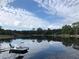 Picturesque lake view featuring a pontoon boat, with the sky and clouds mirrored on the water's surface at 1405 Periwinkle Ave, Deland, FL 32724