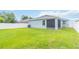 Home's backyard featuring a lush lawn, white fence, and screened-in patio at 141 Sandestin Dr, Haines City, FL 33844