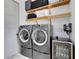Modern laundry room boasts washer, dryer, wine fridge, and wooden storage shelves at 14106 Eliot Ave, Orlando, FL 32827