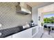 Modern outdoor kitchen with stainless steel grill, black countertop, geometric backsplash, and storage at 14106 Eliot Ave, Orlando, FL 32827