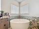 Bright bathroom featuring a soaking tub with decorative tile backsplash and modern fixtures at 16246 Ravenna Ct, Montverde, FL 34756