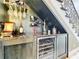 A stylish under-stairs wine bar with a wine fridge, granite countertop, and decorative glassware display at 16246 Ravenna Ct, Montverde, FL 34756