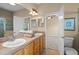 Bathroom with double sink vanity, wood cabinets, and doorway leading to bedroom and water closet at 16729 Tall Grass Ln, Clermont, FL 34711