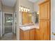 Bright bathroom featuring a vanity with sink, wood cabinets, and a large mirror with decorative lighting at 16729 Tall Grass Ln, Clermont, FL 34711
