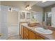 Bathroom with double sink vanity, wood cabinets, and doorway leading to bedroom and glass shower at 16729 Tall Grass Ln, Clermont, FL 34711