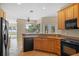 Well-equipped kitchen with wood cabinets, black appliances, and a breakfast bar overlooking the living area at 16729 Tall Grass Ln, Clermont, FL 34711