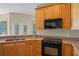 Well-lit kitchen featuring wood cabinets, speckled countertops, and modern black appliances at 16729 Tall Grass Ln, Clermont, FL 34711