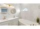 Bright bathroom with a double sink vanity with gold hardware, round mirrors, and marble tile at 17404 Chateau Pine Way, Clermont, FL 34711