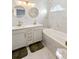 Bright bathroom with a double sink vanity with gold hardware, round mirrors, and marble tile at 17404 Chateau Pine Way, Clermont, FL 34711