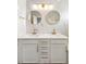 Bright bathroom with a double sink vanity with gold hardware, round mirrors, and marble tile at 17404 Chateau Pine Way, Clermont, FL 34711