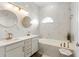 Bright bathroom with a double sink vanity with gold hardware, round mirrors, and marble tile at 17404 Chateau Pine Way, Clermont, FL 34711