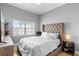 Bedroom with a large, tufted headboard, light grey walls, and a window with a view at 17404 Chateau Pine Way, Clermont, FL 34711