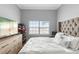 Bedroom with a large, tufted headboard, light grey walls, and a window with a view at 17404 Chateau Pine Way, Clermont, FL 34711