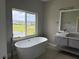 Bright bathroom with a soaking tub by a large window offering views of a pond and community at 2041 Greenbriar Ter, Davenport, FL 33837