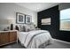 Stylish bedroom featuring a black accent wall, neutral decor, and ample natural light from the window at 2530 Raghav Trl, Tavares, FL 32778