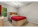 Cozy bedroom with a red bed, built-in headboard, and a window overlooking lush greenery at 359 Westwind Ct, Lake Mary, FL 32746
