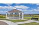 White gazebo overlooks a pond with bench seating and a pathway for relaxation and enjoyment at 3852 Corsican Pl, Lake Alfred, FL 33850
