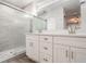 Beautiful bathroom boasts double sinks with white cabinets, quartz counters, and a tiled shower with a glass door at 3902 Brandeis Ave, Orlando, FL 32839