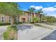 Charming two-story townhome featuring a concrete driveway, lush landscaping and a welcoming arched entryway at 3938 Calabria Ave, Davenport, FL 33897