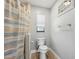 Cozy bathroom featuring a toilet, window, and shower with striped curtain at 5436 Tangerine Ave, Winter Park, FL 32792
