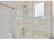 Tiled bathroom featuring a shower over the tub, a frosted window, and a chrome shower head and fixtures at 6233 Rydal Ct, Windermere, FL 34786
