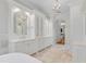 Elegant bathroom with dual vanities, a freestanding tub, a chandelier, and travertine floors at 6233 Rydal Ct, Windermere, FL 34786