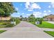 Paver driveway leads to an impressive home with manicured landscaping and mature trees under a blue sky at 6233 Rydal Ct, Windermere, FL 34786