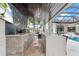 Covered outdoor kitchen boasts a grill, sink, bar seating, and a view of the inviting pool area at 6233 Rydal Ct, Windermere, FL 34786