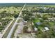 Aerial view of a long straight road reveals an orchard and a home, fenced yards, and more homes further down the street at 8812 Oakwood Dr, Lake Wales, FL 33898