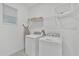 Bright laundry room with washer, dryer, storage shelves and a window for natural light at 9239 Sommerset Hills Dr, Davenport, FL 33896