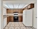 Galley kitchen with wood cabinets, white refrigerator, and geometric tile flooring at 963 Beach Breeze Dr, Orlando, FL 32835