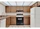 Galley kitchen featuring warm wood cabinets, white refrigerator, and black range at 963 Beach Breeze Dr, Orlando, FL 32835