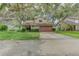 Charming home featuring a two-car garage, lush landscaping, and mature trees draped with Spanish moss at 9948 Timber Oaks Ct # 14, Orlando, FL 32817