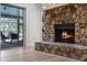 Close-up of a stone fireplace with a wooden mantel, hardwood floors, and sliding glass doors to the outdoor patio at 107 Laurel Oak Dr, Longwood, FL 32779