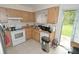 Well-lit kitchen with light wood cabinets, white appliances, and a view of the backyard at 11418 Ashboro Dr, Orlando, FL 32837