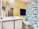Bathroom with a vanity, toilet, large mirror, and colorful fish-themed shower curtain at 2314 Cormorant St, Kissimmee, FL 34743