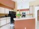 Well-lit kitchen with white cabinetry, a breakfast bar, and essential appliances, offering functionality at 2314 Cormorant St, Kissimmee, FL 34743