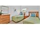 Bright bedroom featuring two twin beds, light green quilted bedspreads, wood headboards, and matching wooden nightstands at 2343 Caravelle Cir, Kissimmee, FL 34746