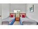 Clean bedroom featuring two twin beds with blue accents, wooden nightstand, and a picturesque window view at 2343 Caravelle Cir, Kissimmee, FL 34746