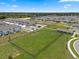Aerial view of a community green space with a large lawn, covered picnic tables, and ample parking at 2372 Orchid Dr, Davenport, FL 33837