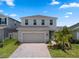 Charming two-story home with a brick-paved driveway, lush landscaping, and attached two car garage at 2372 Orchid Dr, Davenport, FL 33837
