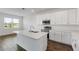 Well-lit kitchen featuring white cabinets, an island with a stainless steel sink, and stainless steel appliances at 3144 Suraj Cir, Tavares, FL 32778