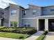 Contemporary two-story townhouse with stone accents, manicured landscaping, and a sidewalk leading to a covered entrance at 456 Ocean Course Ave, Davenport, FL 33896