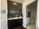 Charming kitchenette with dark cabinetry, quartz countertop, and a peek into the well-lit bathroom at 5328 Teirgarten St, St Cloud, FL 34771
