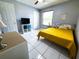 Bright bedroom with white-tiled floors, a yellow bedspread, and a window with natural light at 5815 England Ave, Orlando, FL 32808