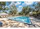 Bright swimming pool with lounge seating in community surrounded by mature trees at 5815 England Ave, Orlando, FL 32808