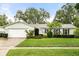 Charming single-story home with manicured lawn, lush landscaping, and white exterior at 7011 Archwood Dr, Orlando, FL 32819