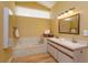 Bright bathroom featuring bathtub, window and & sink with large mirror at 8143 Terragona Ct, Orlando, FL 32836