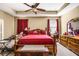 Cozy bedroom featuring a large bed with red bedding, wood furniture, and a ceiling fan for added comfort at 969 Springs Landing Dr, Deltona, FL 32725